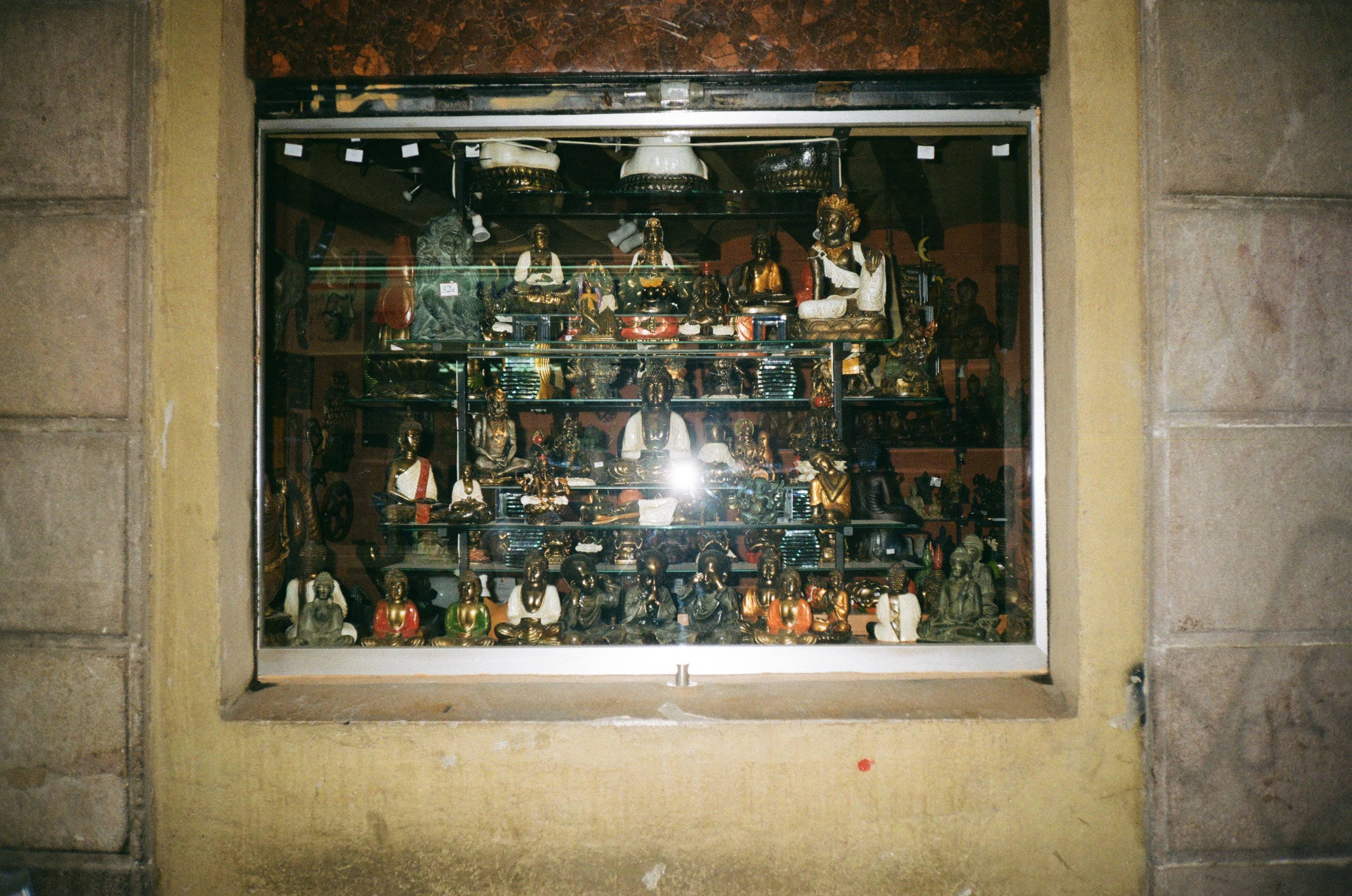 Window display of a unique boutique showcasing a variety of handcrafted and vintage statues, highlighting a distinct brand identity