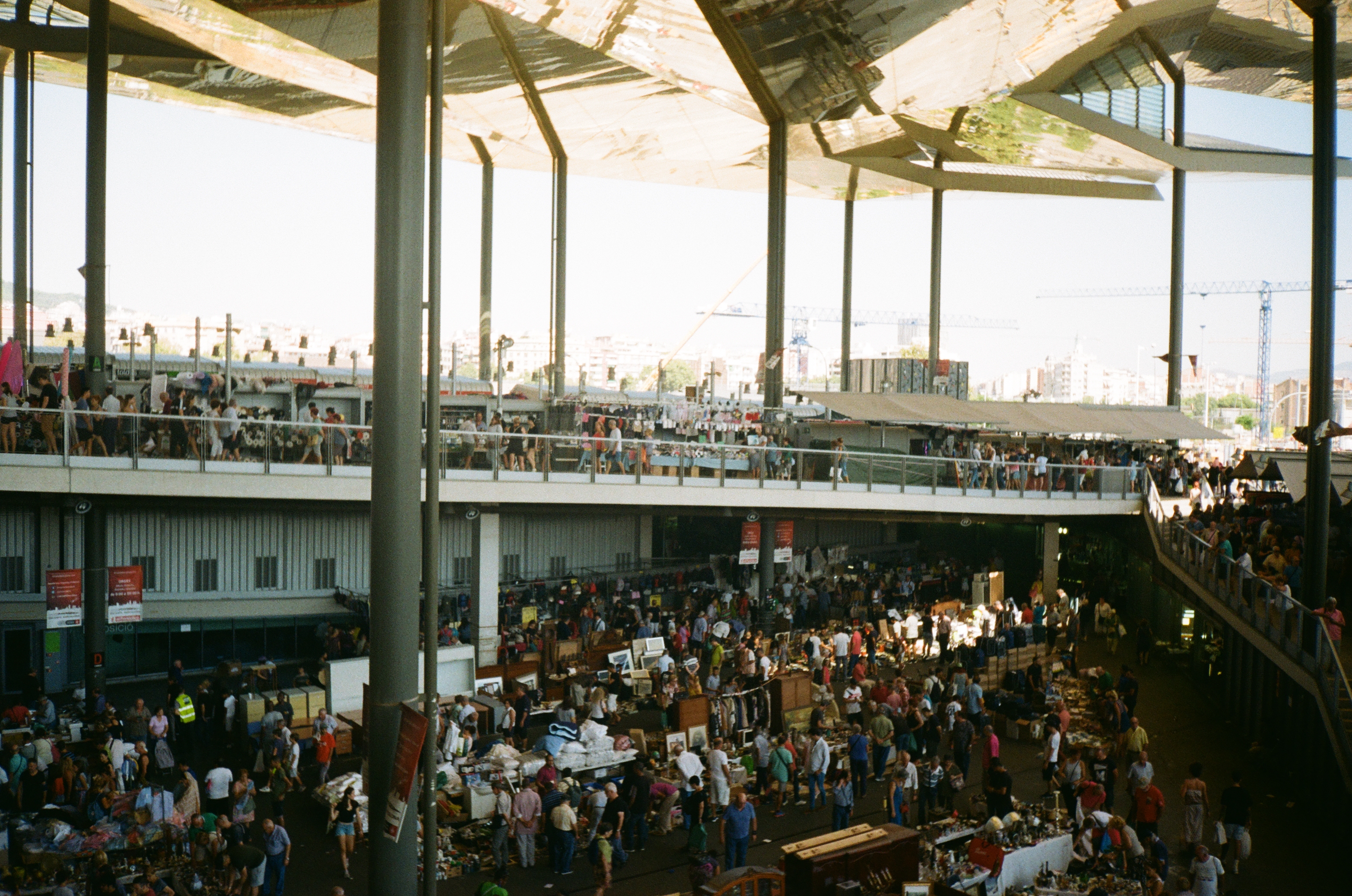 Vibrant marketplace with multiple vendors and a bustling crowd, showcasing a wide variety of products under a modern roof structure